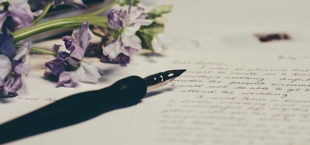 fountain pen, paper and flowers on a table